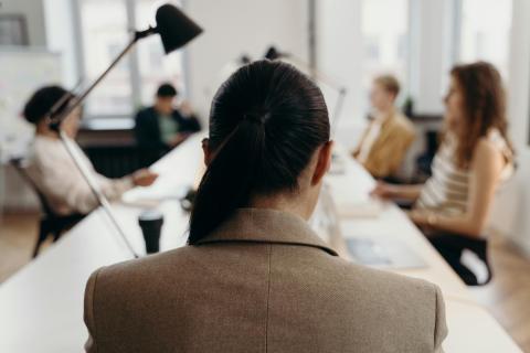 Blurred Image of a Woman Sitting at the End of Table for a Work Meeting 